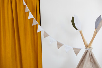 Multi-colored festive garland of flags with Child teepee wigwam for play. Decor for holiday. Stylish children room with hanging cotton flags. Decoration for baby room. Baby Shower party. Kid Holiday.  © stock_studio