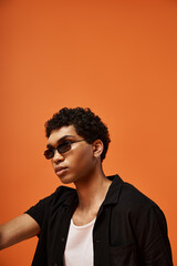 Obraz premium Stylish young man with curly hair showcases fashion in vibrant studio setting