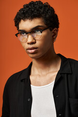 Fototapeta premium Stylish young man with eyeglasses poses confidently in vibrant studio setting
