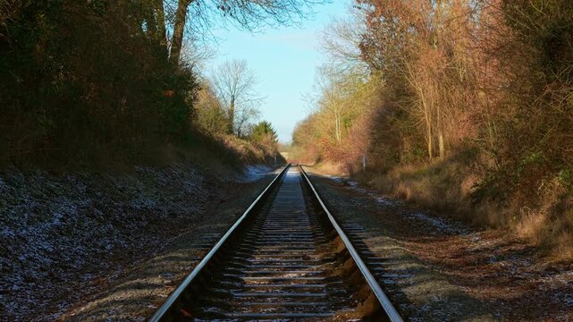 Train moving forward along railway tracks through forest corridor first person view. Train traveling straight ahead on rails across winter landscape with trees lining route POV. Train continuing