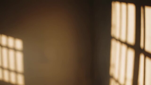 Sunlight casting strong, linear shadows from a window frame onto a pristine, neutral colored wall and wooden floor creates an abstract pattern and peaceful atmosphere in an empty room interior