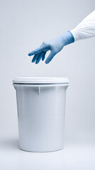 Gloved hand reaching toward white medical waste bin in clinical setting conveying biosafety and disinfection practice