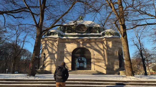 Der verschneite Hubertusbrunnen in Muenchen, Bayern. Ein bedeutendes Kulturdenkmal am Nymphenburger Kanal bei Wintersonne. Klassische Architektur von Adolf von Hildebrand und Carl Sattler.