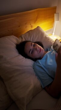 woman uses phone late, quiet night scene of fatigued lady engaging with her mobile device in bed