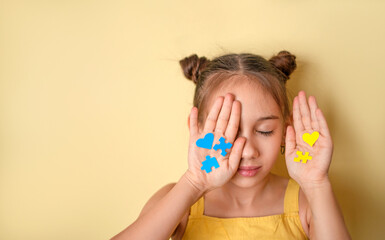 Young child covering eyes with hands holding puzzle hearts. Inclusion, diversity, disability...