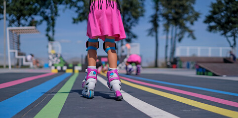 Child wearing protective gear roller skating at an outdoor skate park. Active childhood, learning...