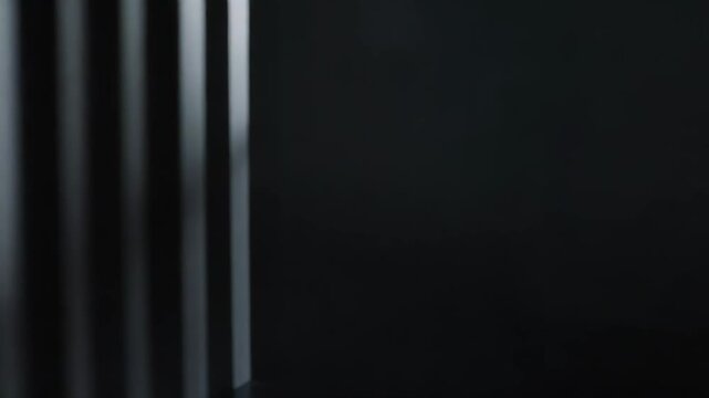 Vertical lines of light and shadow create a repetitive abstract geometric pattern, reflecting on a dark surface and conveying modern design, contrast, and depth