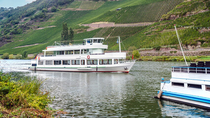 Passenger ship sailing on moselle river surrounded by vineyards in Traben Trabach