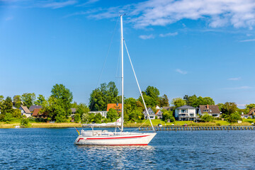 Sailing boat floating on calm water near residential houses