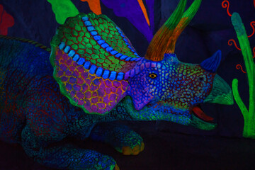 Neon Glow-in-the-Dark Triceratops Dinosaur Statue in Fantasy Blacklight Cave. © KAJORN STUDIO