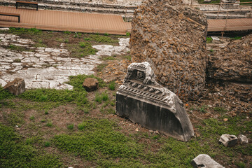Naklejka premium Ancient Roman Ruins with Stone Fragment and Grass at Archaeological Site