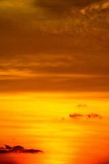 Obraz premium Vertical composition of a deep orange sunset sky with layered clouds.