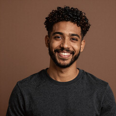 Obraz premium Studio portrait of a confident, charming young man with curly hair and beard in warm brown background