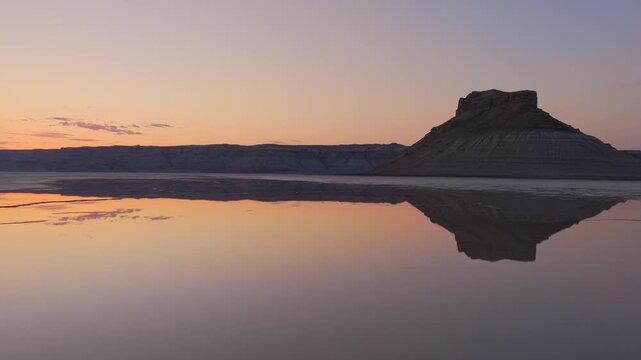 Aerial view of the still waters reflecting the land formation at Karynzharyk mirroring the pastel sunset, Karynzharyk, Mangystau Region, Kazakhstan.