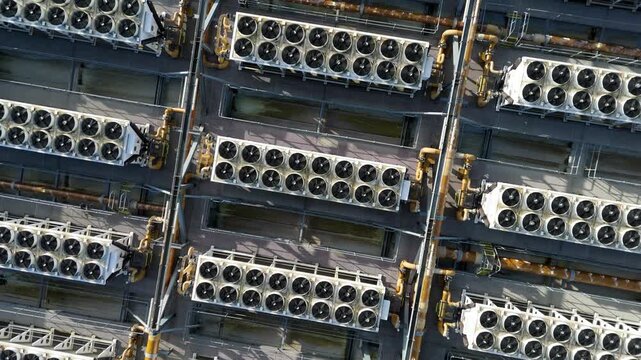 Aerial top down view of symmetrical rows of industrial cooling fans and ventilation systems on a data center rooftop for AI computing infrastructure.