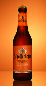A bottle of Schofferer Heilweizen beer is shown in a bright orange background