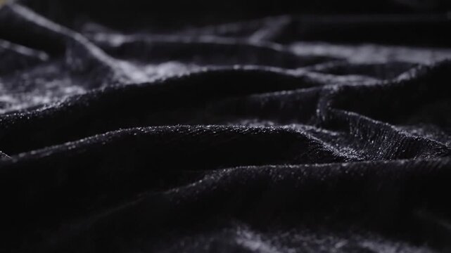 Close-up of flowing black velvet fabric with subtle glitter and texture