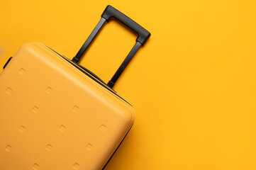 Fototapeta premium Travel, vacation, trip, and flight concept. Stylish yellow plastic suitcase with black handle on yellow background, flat lay top view. Baggage, comfortable suitcase for clothes, minimalist summer back