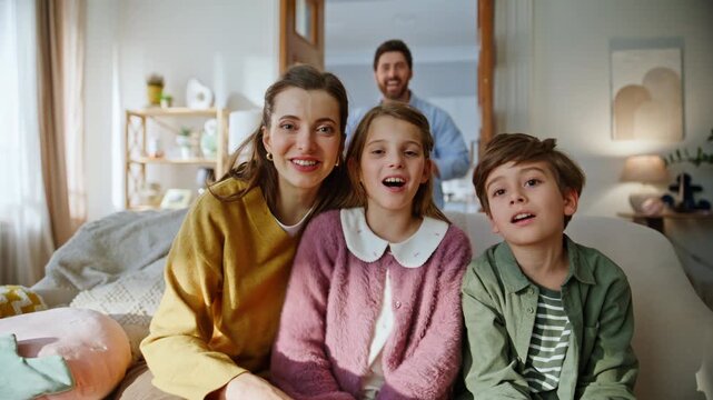 Pov mother kids greeting webcam sitting cozy couch closeup. Father entering room