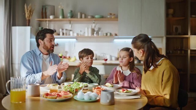 Happy relatives dinning kitchen table closeup. Family having breakfast clapping