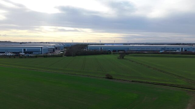 Aerial drone view over Symmetry Park logistics hub in Biggleswade featuring massive distribution warehouses and HGV shipping traffic in England UK.