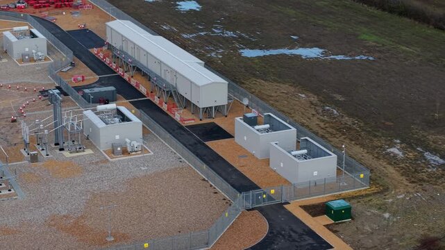 Close up aerial view of 400kV substation featuring supergrid transformers and high voltage pylons for the Great Grid Upgrade near Biggleswade United Kingdom. 