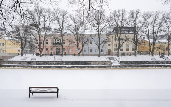 Bench, historic buildings on the frozen Aurajoki River, wintery Turku or Swedish &Aring;bo, Varsinais-Suomi, Finland
