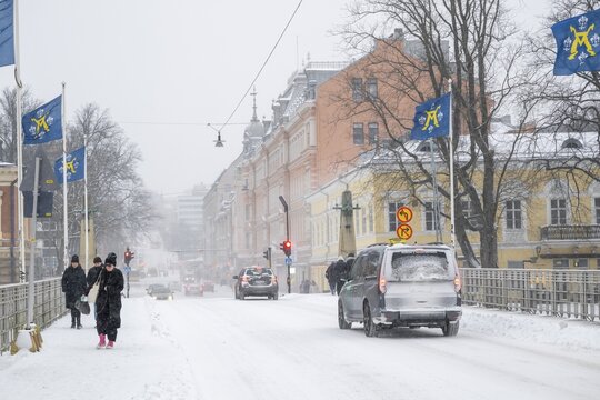 Pedestrians and cars on the snow-covered Auransilta bridge that crosses the Aurajoki River, wintery Turku or Swedish &Aring;bo, Varsinais-Suomi, Finland