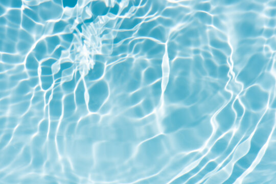 Blue water with ripples on the surface. Defocus blurred transparent blue colored clear calm water surface texture with splashes and bubbles. Water waves with shining pattern texture background.