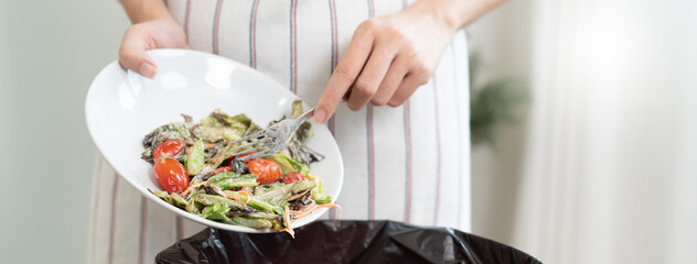 The housewife is throwing the leftover food from the meal into the bin