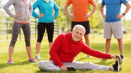 Obraz premium Elderly man stretching with group in park