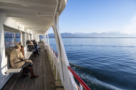 Passengers sitting on the outside deck of a passenger ship, view of Lake Constance with mountain panorama, Bavaria, Germany