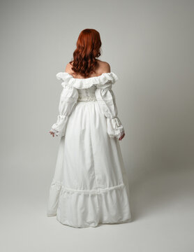 full length portrait redhead female model wearing historical fantasy wedding dress, fairytale ball gown.  posing walking away from camera, isolated figure on white studio background