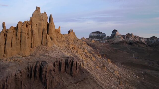 Aerial view of dramatic sandstone formations under a pastel sky, showcasing earth tones meeting the horizon, Shetpe, Mangystau Region, Kazakhstan.