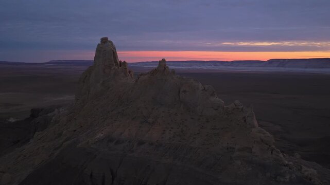 Aerial view of a geological formation, with rugged, eroded rock formations, under a colorful sky, hues of pink and blue, Shetpe, Mangystau Region, Kazakhstan.