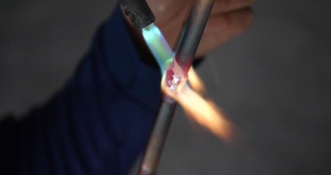 A technician or worker is soldering copper pipes; an air conditioning technician.