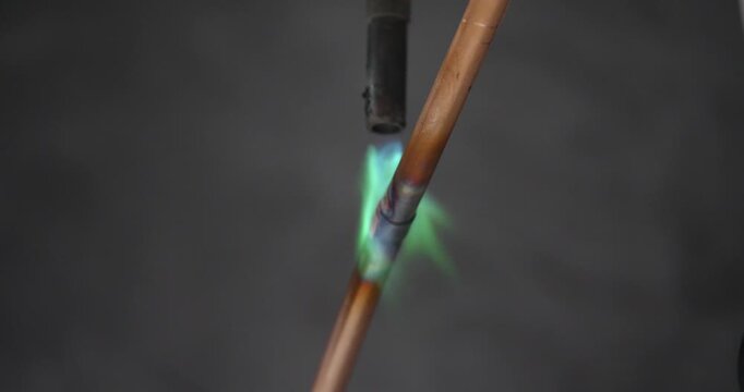A technician or worker is soldering copper pipes; an air conditioning technician.