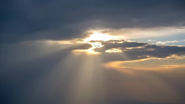 Rays of sunlight breaking through dark storm clouds at sunset  