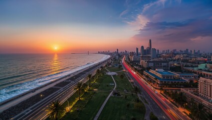 Showing highway curving along beach and park with palm trees at sunset with vehicle light trails