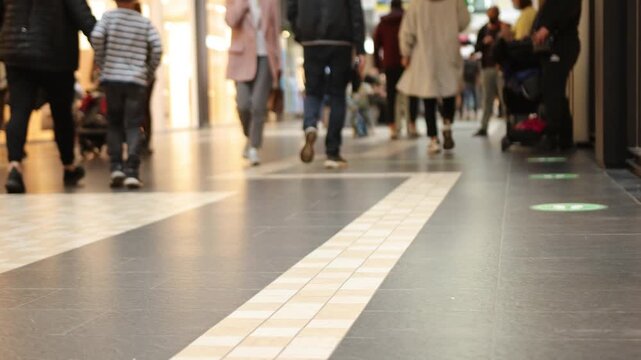 people walking, shopping mall, crowd walking. Crowd of people in mall during shopping time, close up of legs holding shopping bags, selective focus, modern floor and crowd walking along it