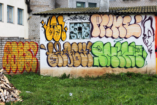 This image captures a vibrant display of street art and graffiti on a white-walled building, photographed in Ostrovets, Belarus, in 2012