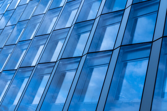 Blue glass architecture facade with modern windows pattern and reflection showing corporate building design with abstract geometry and clean texture
