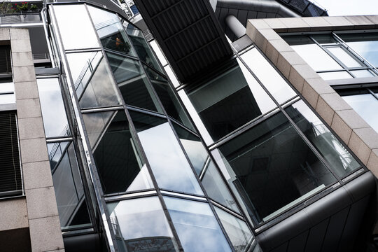 Modern urban architecture building facade with glass and steel angular structure seen in perspective highlighting sharp design geometry and reflection