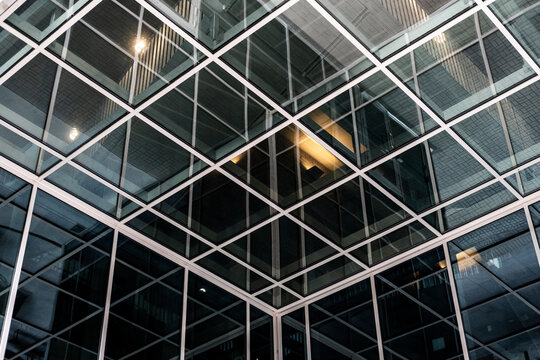 Modern architecture facade with glass grid pattern and diagonal geometry showing reflection and rich texture in an abstract design detail closeup