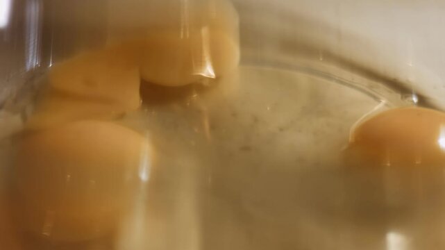Cracked eggs in a glass bowl, macro view