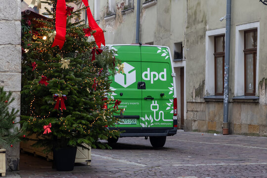 Krakow, Poland - December 2, 2025: DPD electric delivery van parked on festive urban street with Christmas lights and bows, delivering important holiday packages
