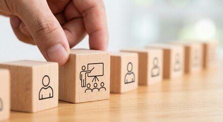 Hand choosing wooden block with training icon for business coaching and education concept