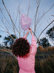 Obraz premium Outdoor pink scarf woman reaching toward a leafless tree under a bright sky, capturing nature, motion and calm in a vivid field scene with soft light and wind