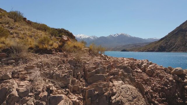 Aerial fly by of the rocky shores of lake Potrerillos in Mendoza, Argentina.