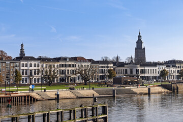 Fototapeta premium Zutphen city skyline along the IJssel river featuring historic white houses, the church tower, and the modern quay with stairs.